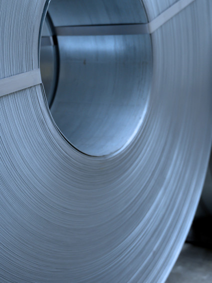 Large steel coils neatly stacked and secured with metal bands in an industrial storage area.