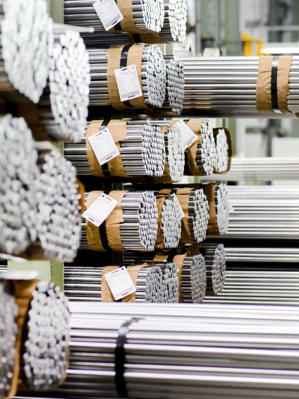 Stacks of neatly bundled stainless steel rods stored in an industrial warehouse.