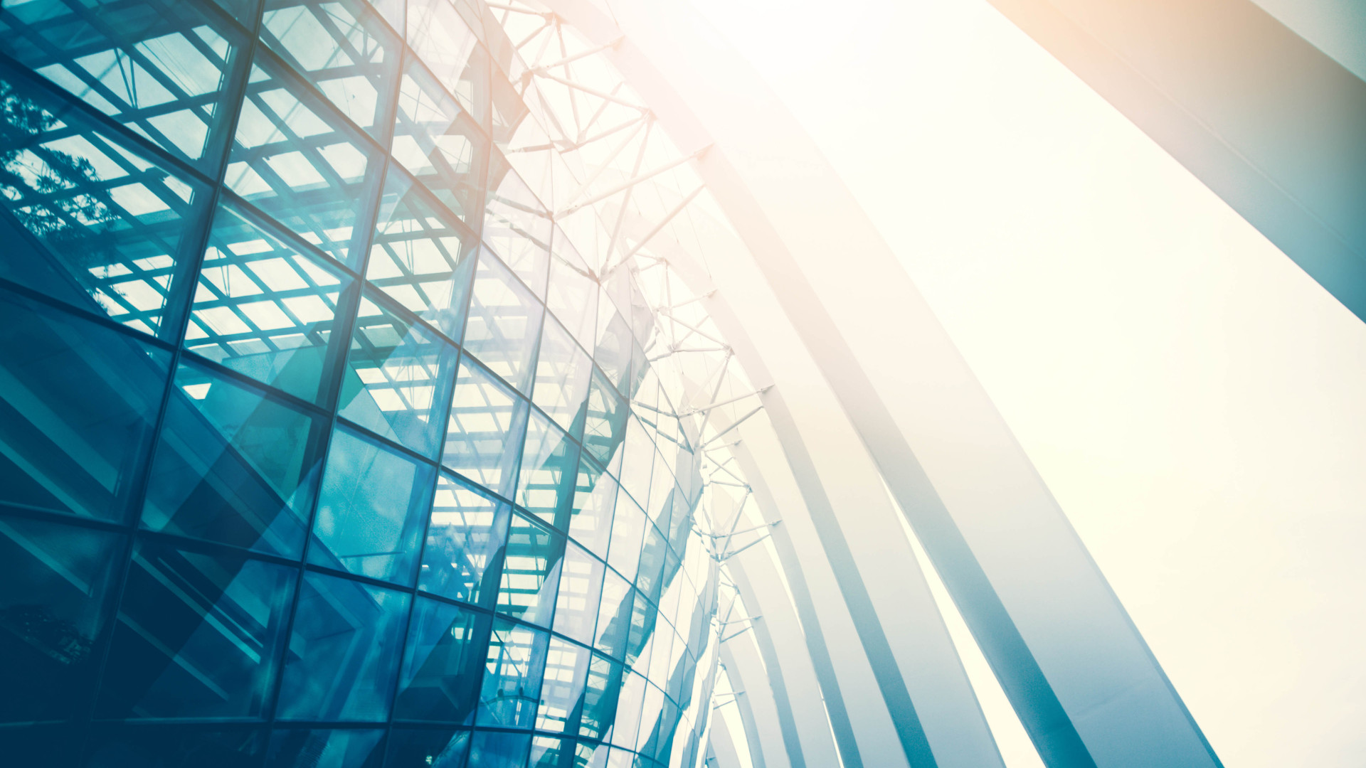 A modern glass and steel building with a futuristic architectural design, reflecting sunlight.